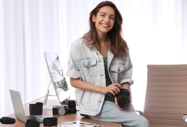 Arbeitsschutz für Medien- und Kreativbetriebe: Fotografin mit Kamera an ihrem Arbeitsplatz im Studio