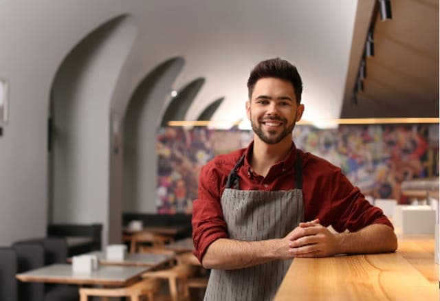 Arbeitsschutz in der Gastronomie: Gastronom hinter dem Tresen seines Cafés