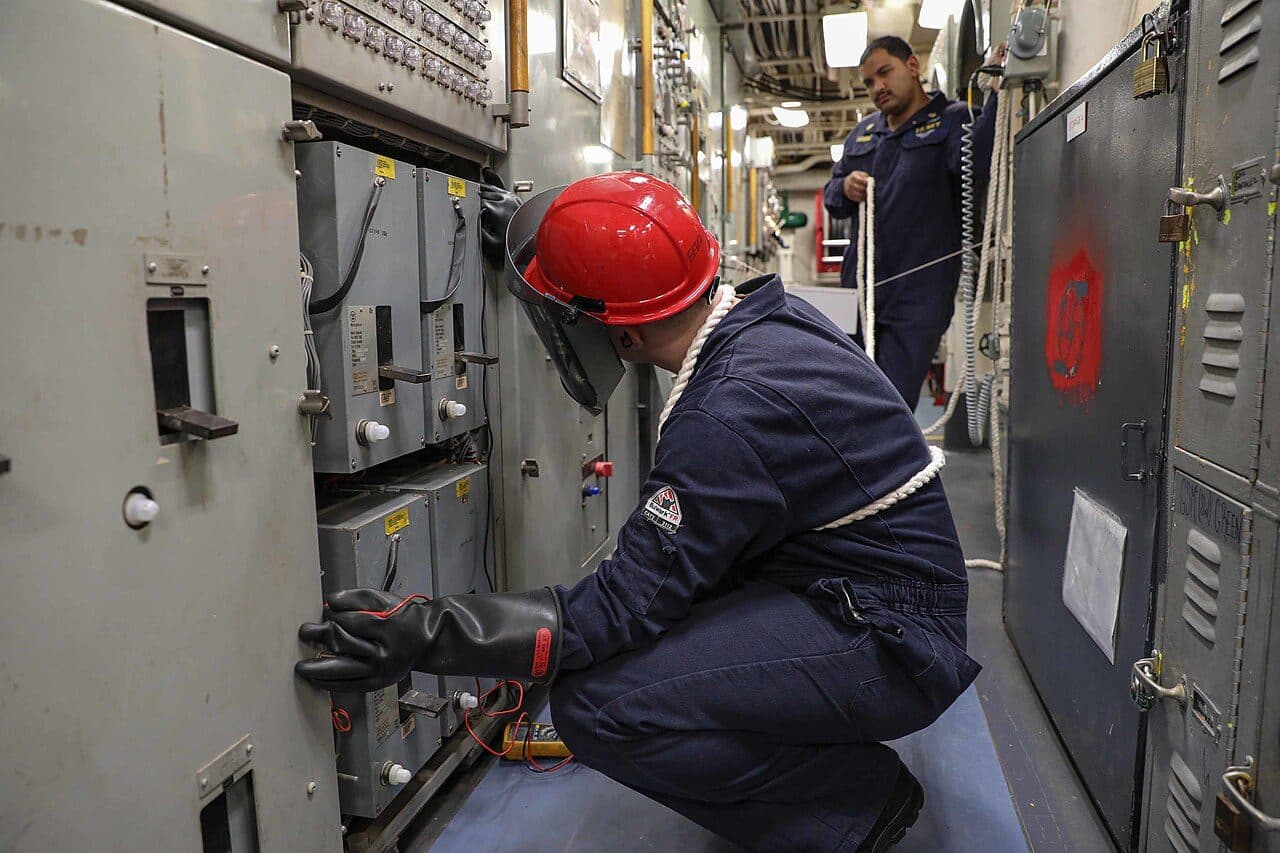 DGUV-V3-Prüfung: Elektriker mit Schutzhelm misst an einer Schaltanlage